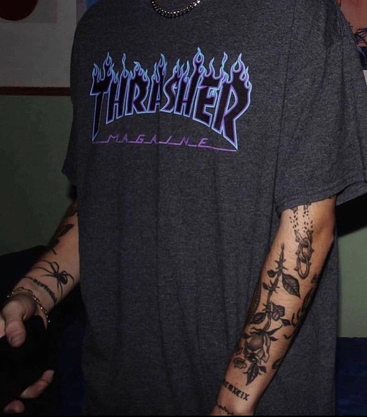 a young man with tattoos on his arm and arms, wearing a thrash t - shirt