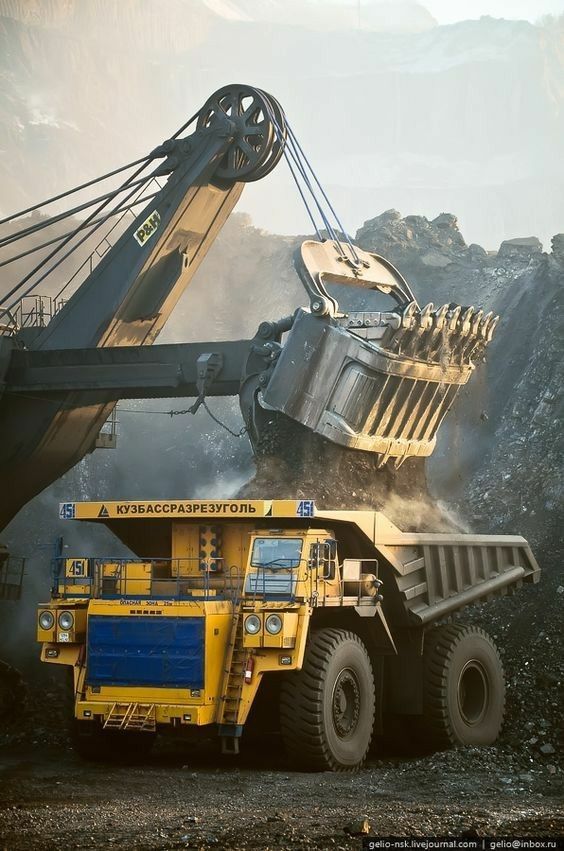 a dump truck is dumping coal into the back of it's loader at a mine site