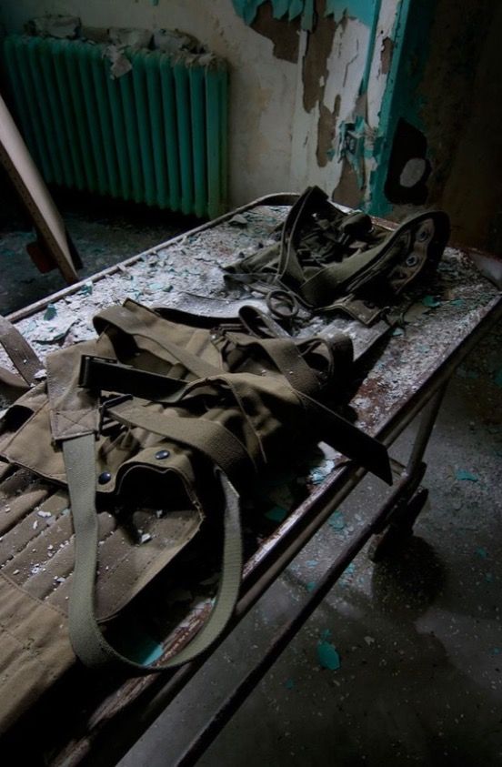 an old bag is laying on top of a bed in a run down room with paint peeling off the walls