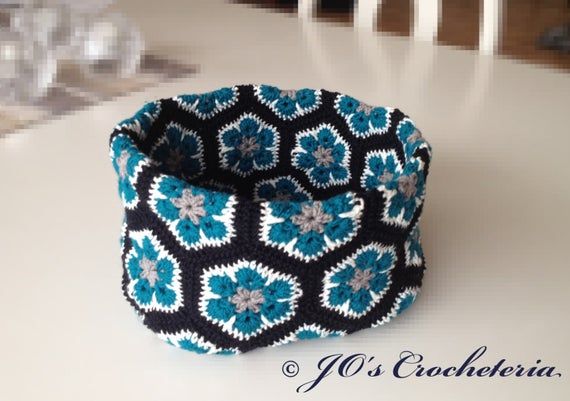 a blue and black flowered fabric basket sitting on top of a dining room table