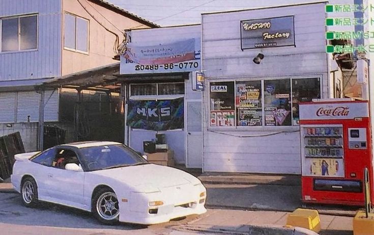 a white sports car parked in front of a building next to a red fire hydrant