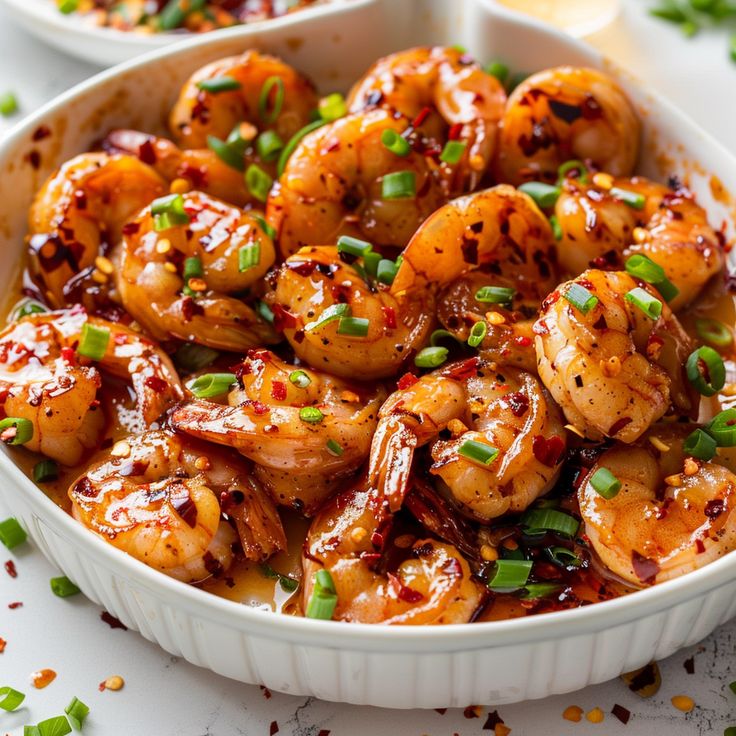 a white bowl filled with cooked shrimp and green onions