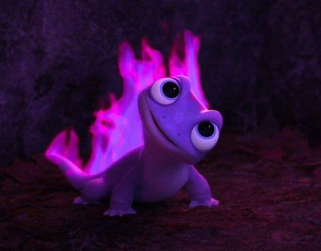 a purple toy with big eyes and flames on it's back legs, sitting in front of a rock wall