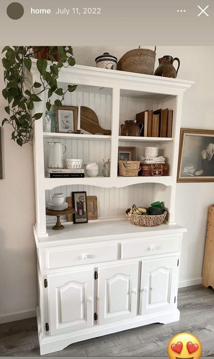 a white hutch with books and other items on the shelves in front of it