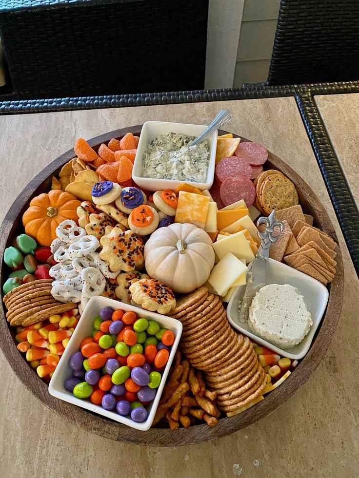 a wooden platter filled with lots of different types of candy and crackers on top of a table