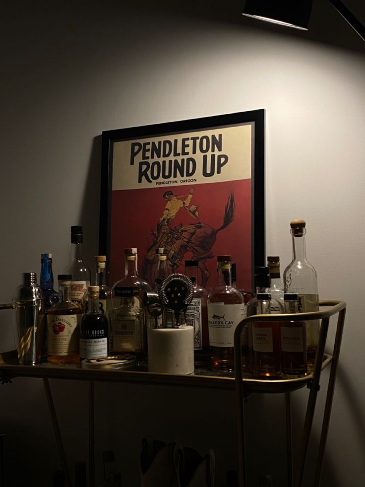 a table with liquor bottles on it and a framed poster above the bar area behind it