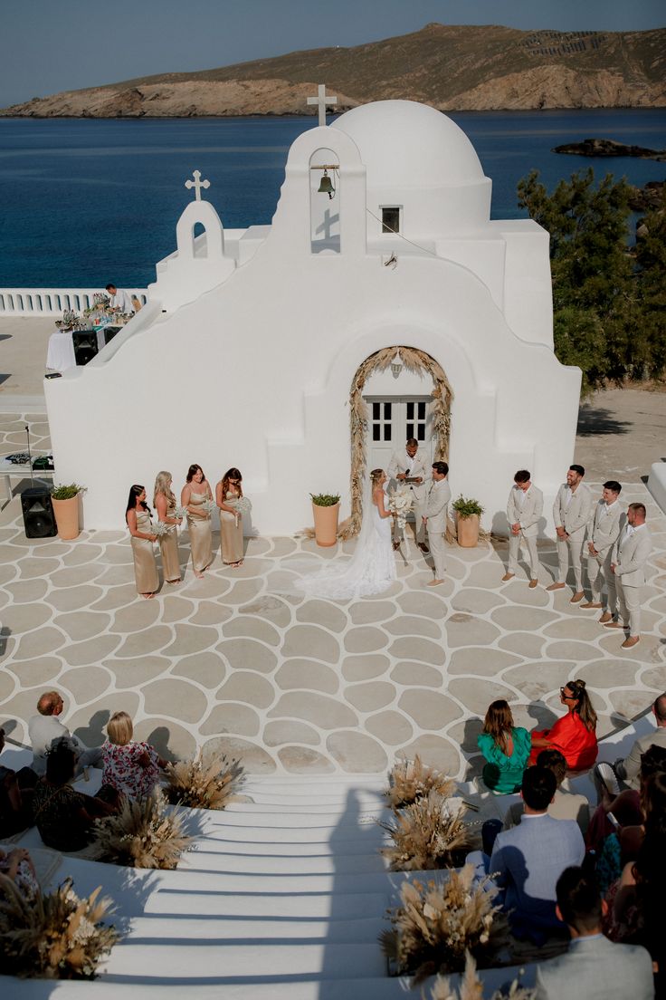 a group of people that are standing in front of a white building and some water