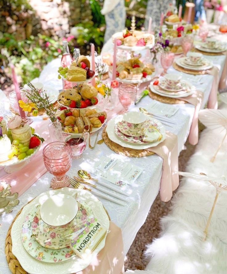 a table set with plates, cups and saucers for a tea party in the garden