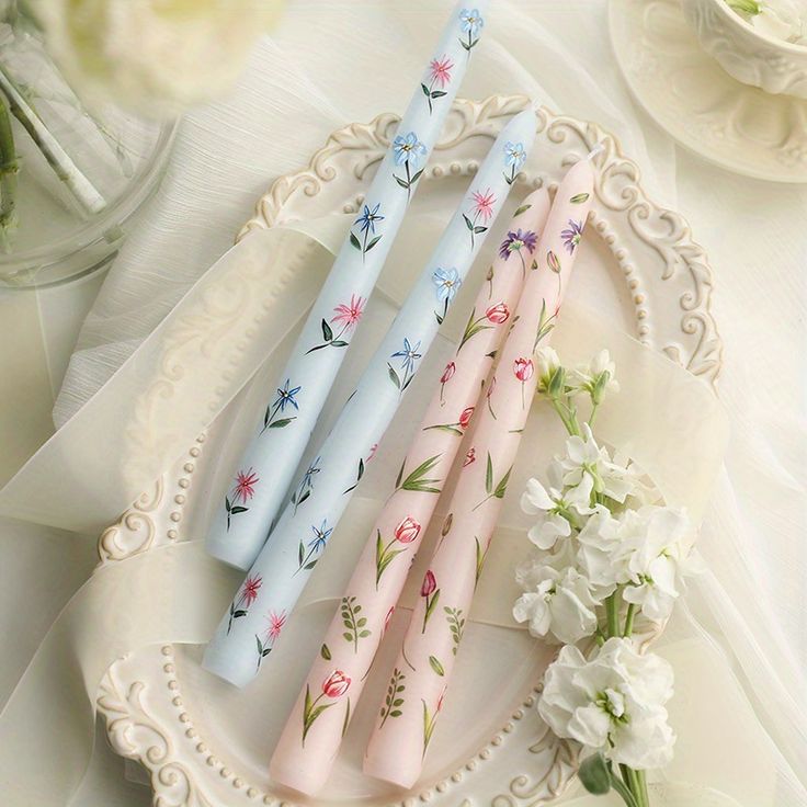 three different colored straws sitting on top of a white plate next to some flowers