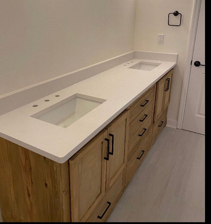 a white counter top in a bathroom next to a wooden cabinet with drawers and knobs