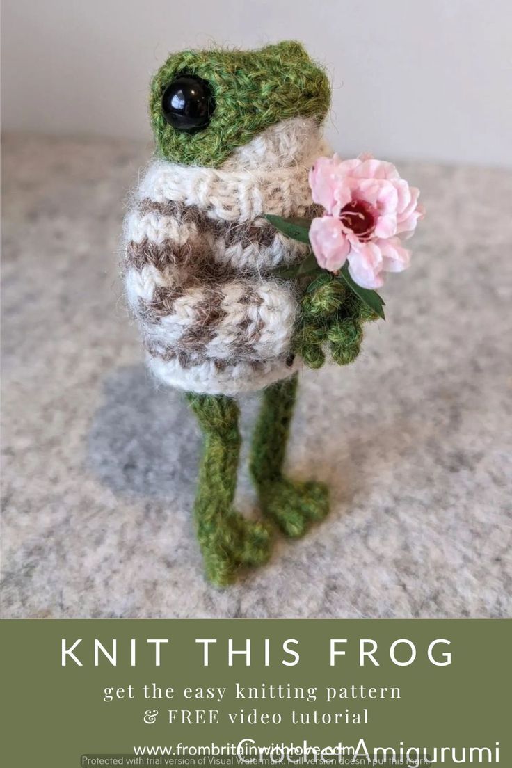 a crocheted frog holding a pink flower