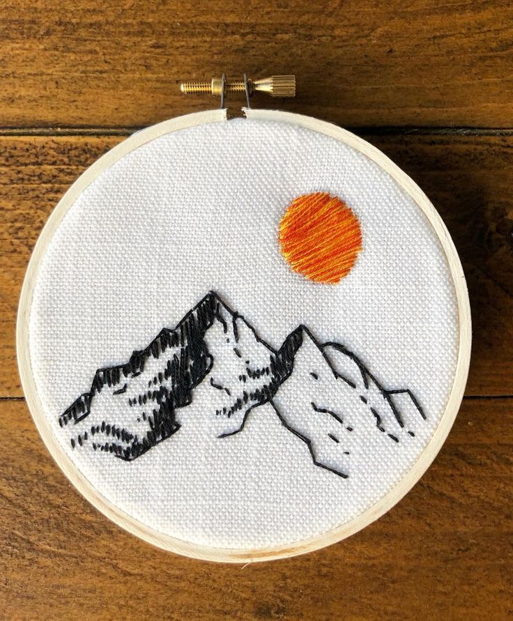 a small embroidery project with mountains and an orange sun