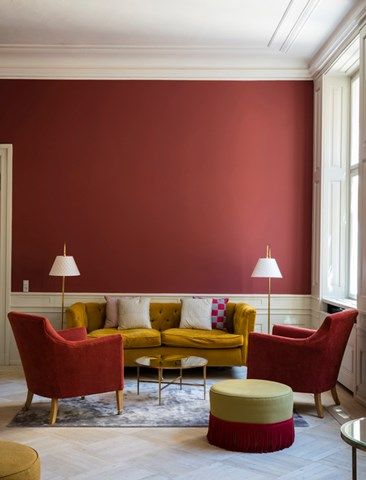 a living room with red walls and two chairs in the corner, one chair is yellow