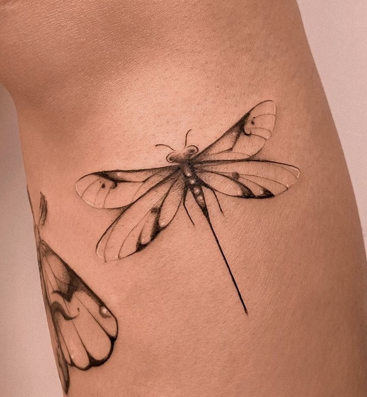 a woman's thigh with a tattoo of a dragonfly on the side and wings