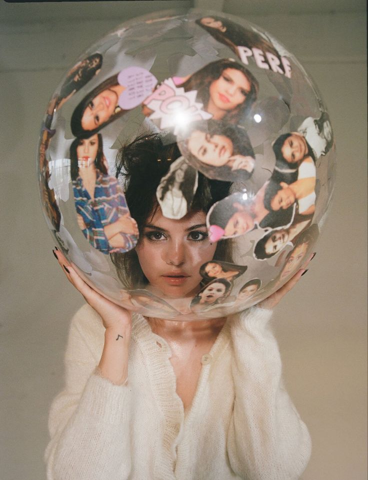 a woman holding up a large clear ball with pictures on it's face and behind her head