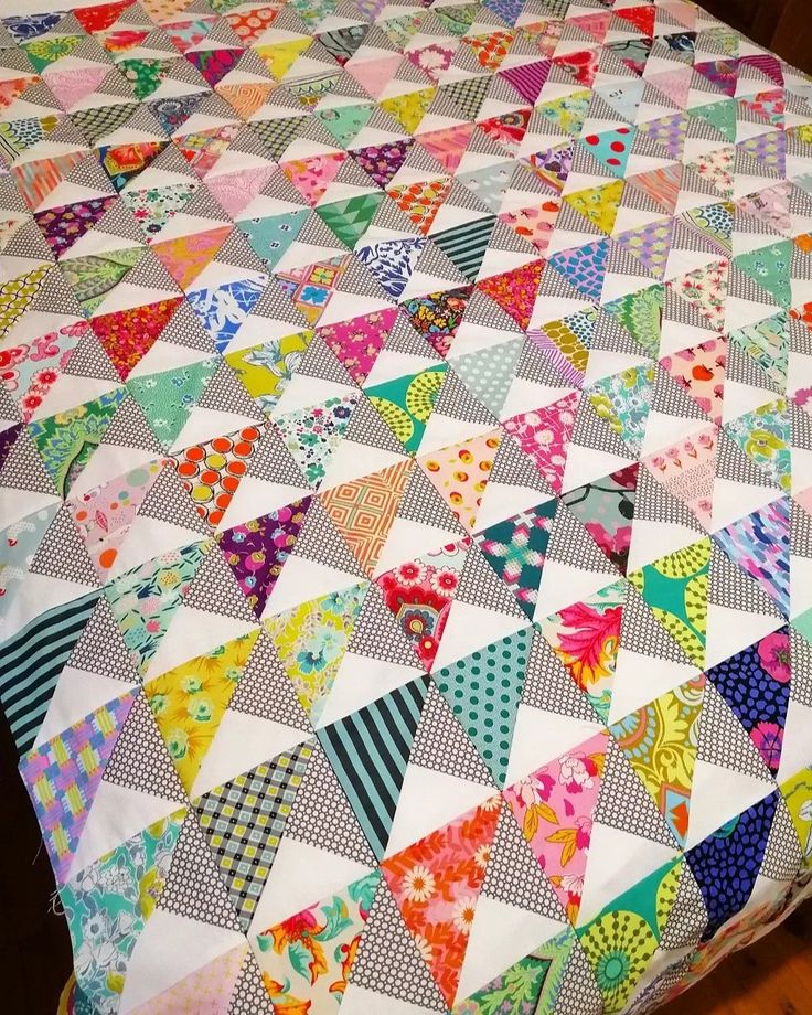 a colorful quilt is laying on top of a bed