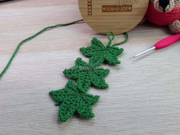 a crocheted christmas tree ornament next to a knitting needle