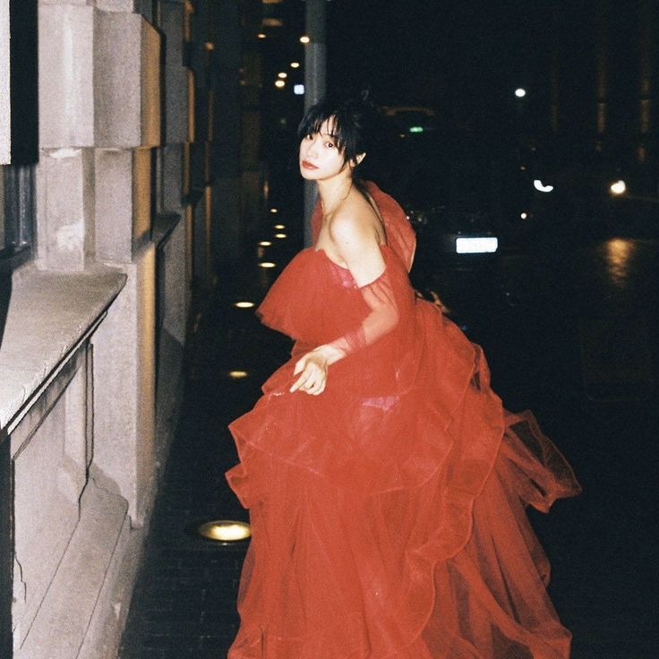 a woman in a red dress is walking down the street