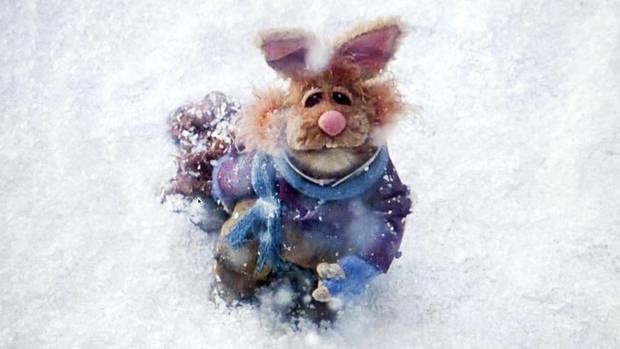 a stuffed animal in the snow wearing a scarf