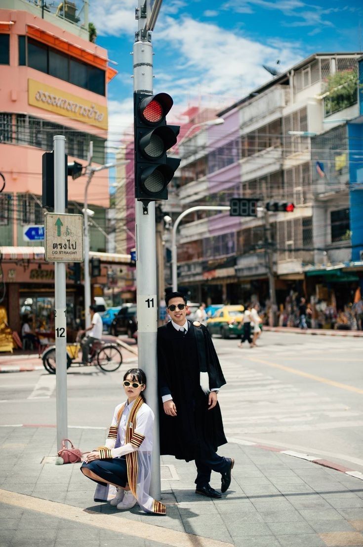 a man and woman standing next to a traffic light on the side of a road