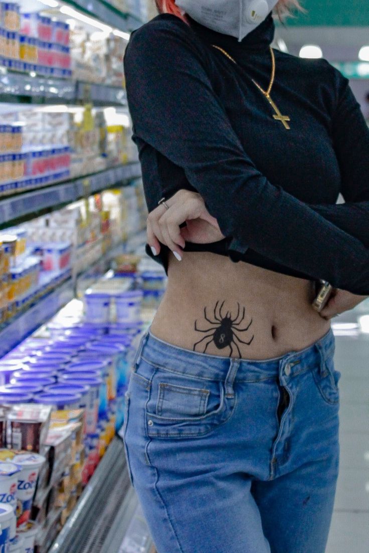 a woman with a spider tattoo on her stomach in a grocery store, wearing a face mask