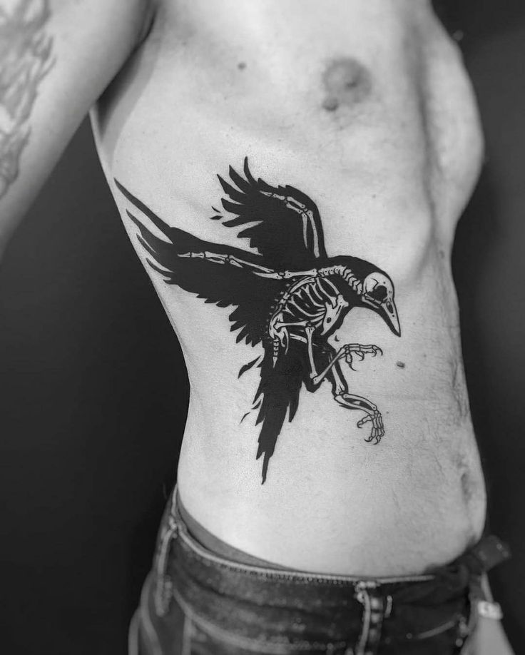 a black and white photo of a man's chest with a bird tattoo on it