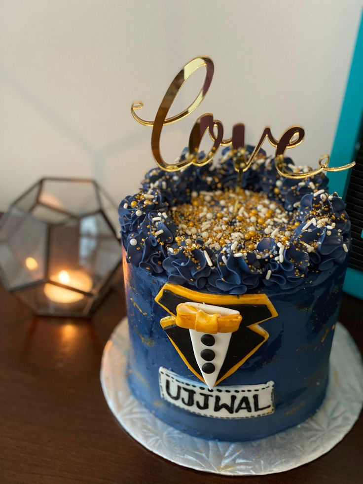 a blue cake with gold sprinkles and the word love on top is sitting on a table