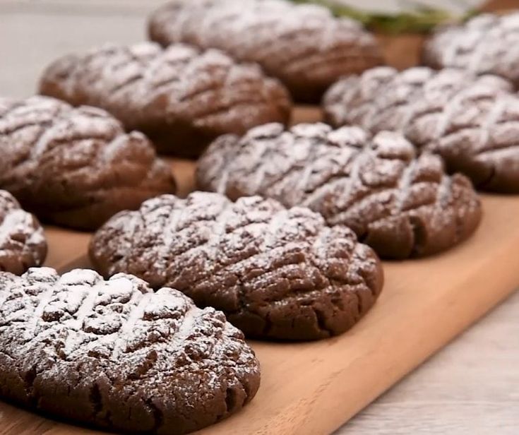 chocolate cookies with powdered sugar on a cutting board