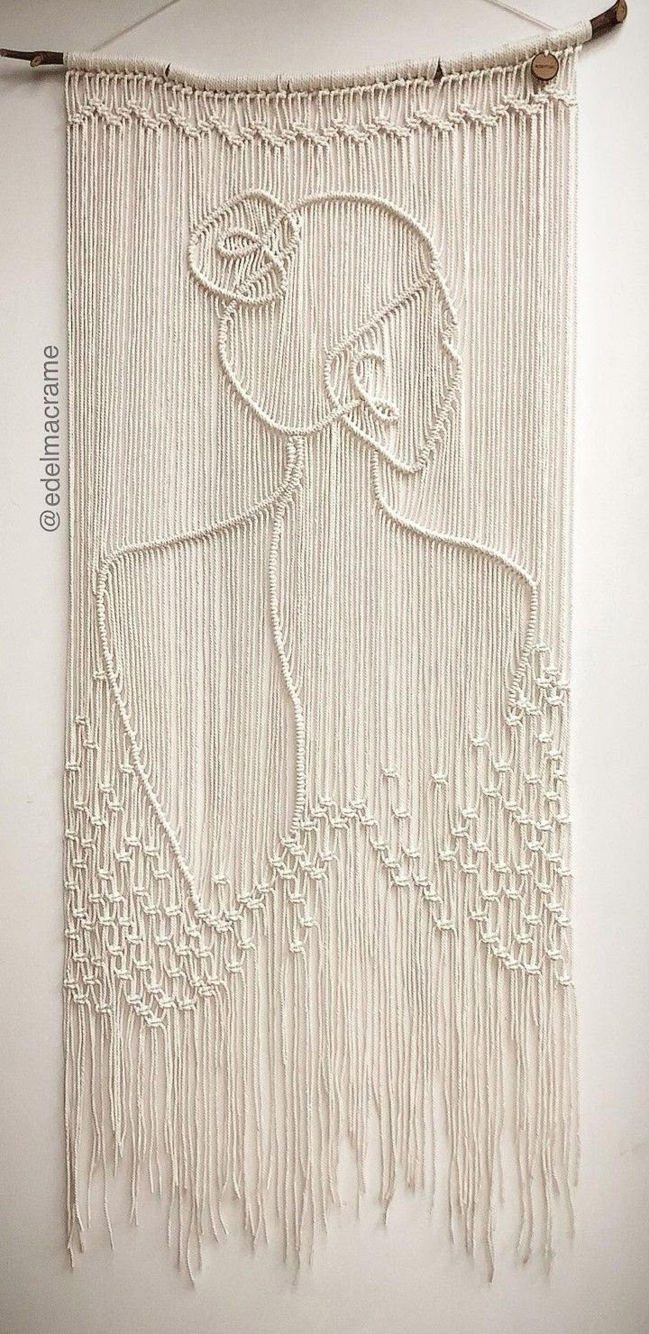 a white wall hanging with a woman's face drawn on it and fringes