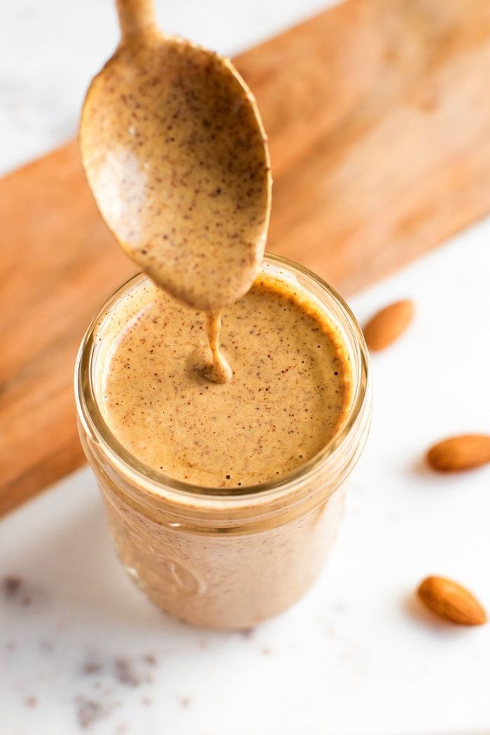 a spoon is pouring almond milk into a jar