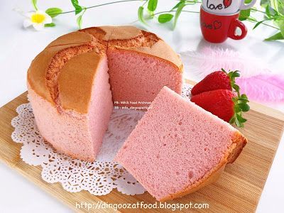 a cake that has been cut in half and is on a cutting board next to some strawberries