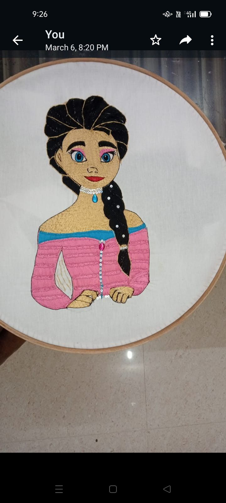 an embroidered picture of a woman in a pink dress with a black cat on her shoulder