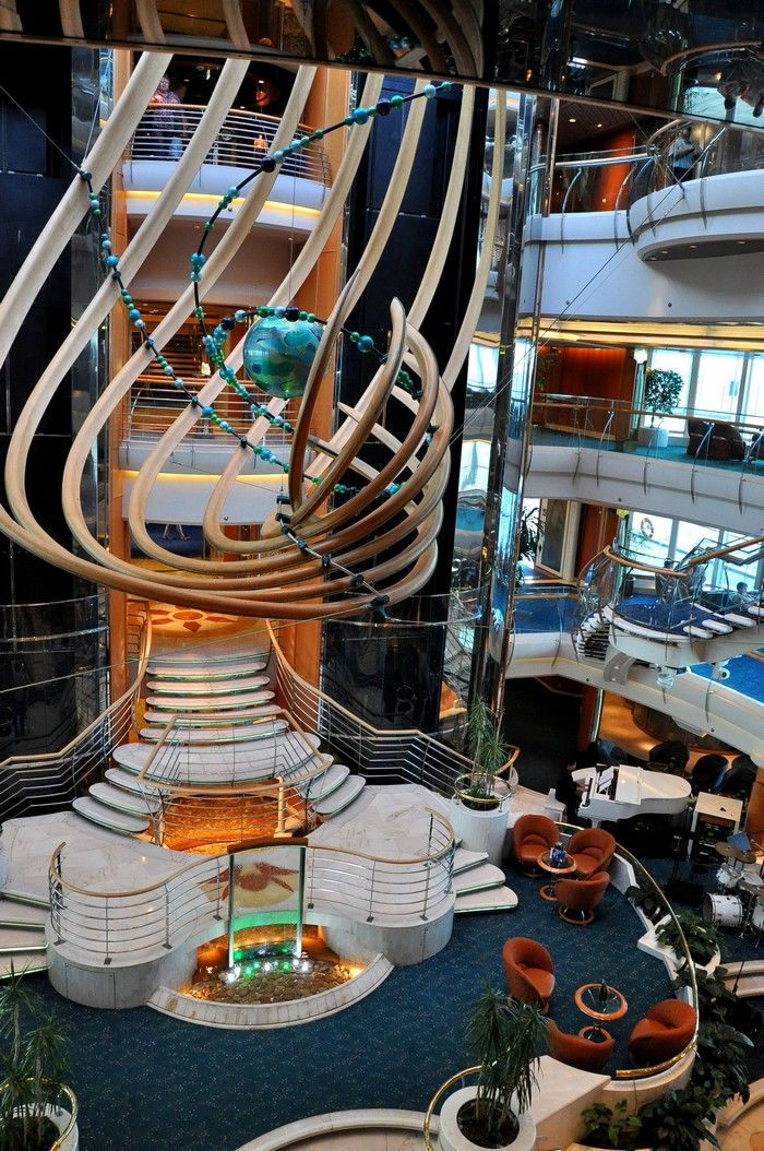 the inside of a large cruise ship with many seating areas and stairs on each side