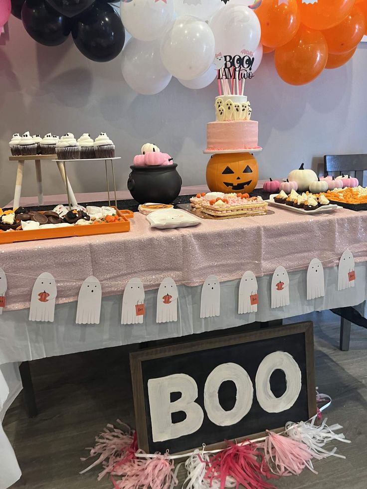 a table topped with lots of desserts next to balloons and halloween themed decorations on top of it