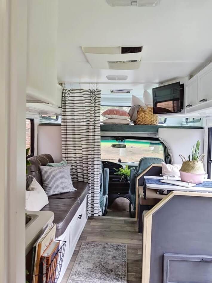 the interior of a camper with couches, cabinets and windows on each side