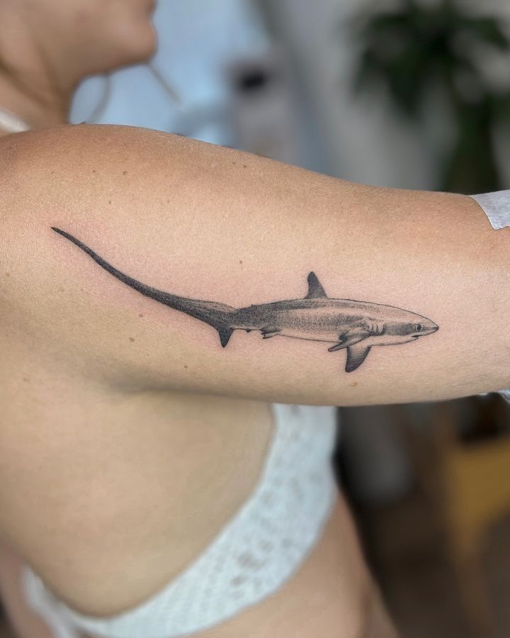 a woman's arm with a shark tattoo on the left side of her body