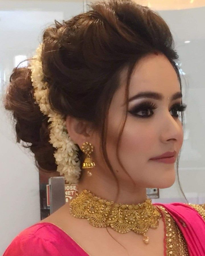 a woman in a pink sari with gold jewelry on her neck and headpiece