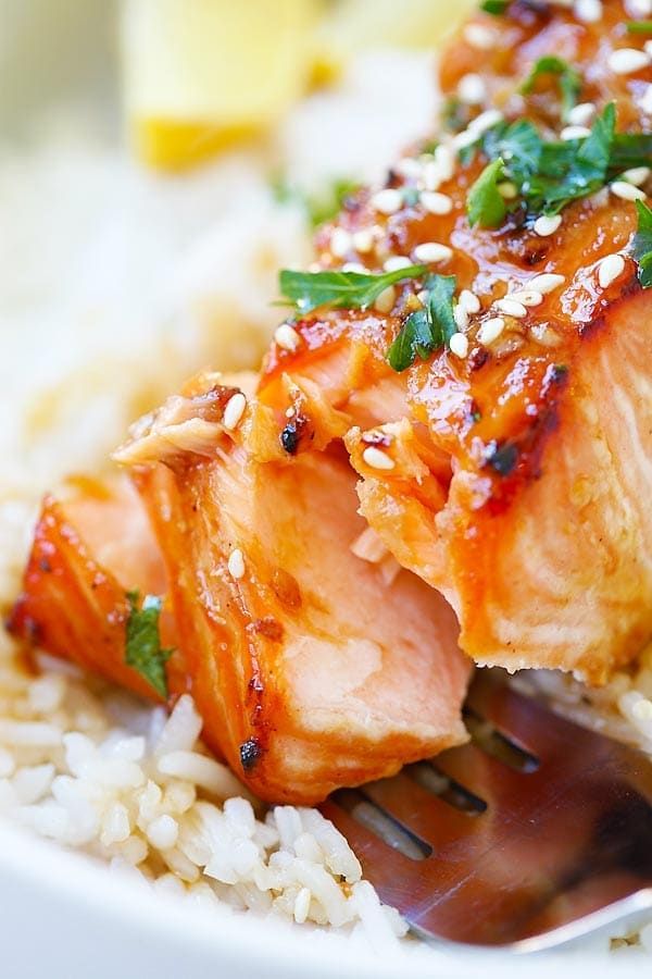 salmon and rice on a plate with a fork in the foreground, topped with green garnish