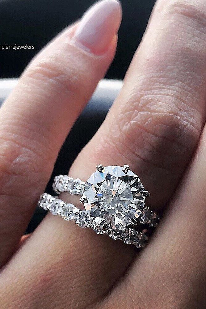 a woman's hand with a diamond ring on top of her finger and the other hand holding an engagement ring