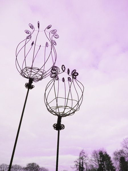 two metal vases sitting next to each other on top of a grass covered field