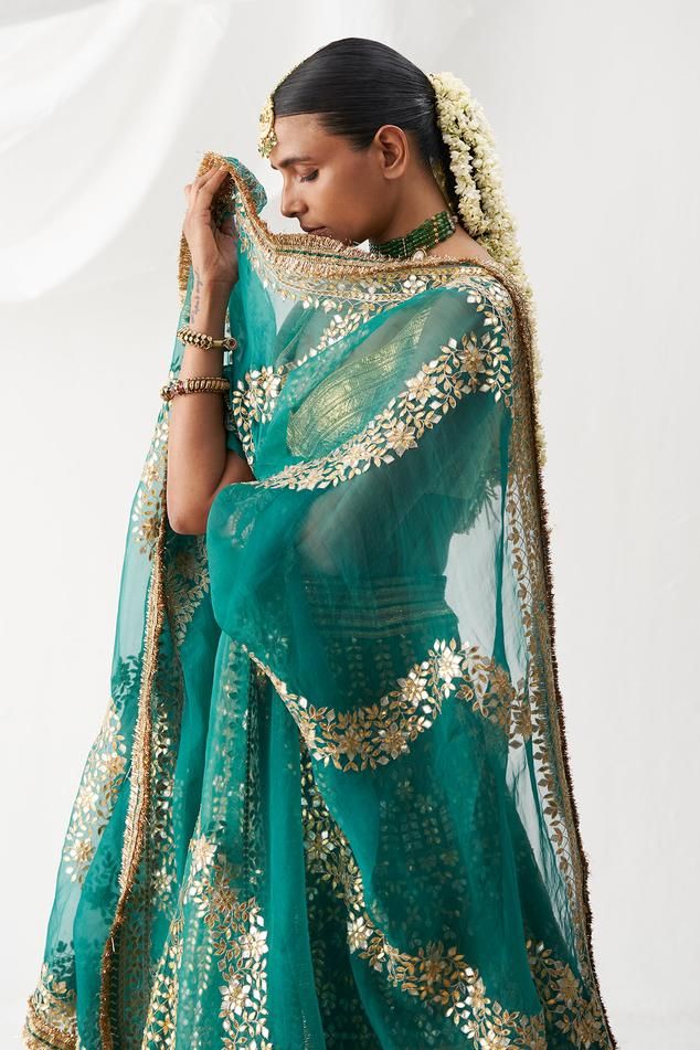 Bright shade of green lehenga with attached cancan and gota patti embroidery. Comes with gold lampi padded blouse and dupatta.
Components: 3
Pattern: Hand Embroidered
Type Of Work: Gota Patti
Neckline: Leaf
Sleeve Type: Sleeveless
Fabric: Lampi
Color: Green
Other Details: 
Floral patterns
Kiran lace hem dupatta
Attached lining
Approx. product weight (in kgs): 6
Length:
Blouse: 13 inches
Lehenga: 44 inches
Occasion: Wedding - Aza Fashions Green Choli With Cutdana For Reception, Green Cutdana Dupatta For Reception, Pista Green Choli With Gota Work In Traditional Drape, Festive Pista Green Pre-draped Saree With Gota Work, Green Sharara For Reception And Navratri, Green Chanderi Lehenga With Cutdana, Pista Green Lehenga With Gota Work In Traditional Drape, Pista Green Dupatta With Gota Work For Reception, Pista Green Sharara With Gota Work For Reception