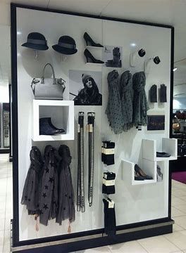 a display case filled with lots of clothes and hats on top of white shelves next to a tiled floor