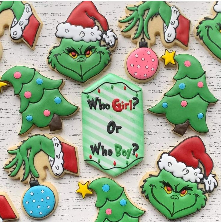 decorated cookies with grin's face and christmas tree decorations on the top one says who girl? or who boy?