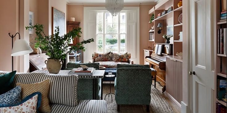 a living room filled with lots of furniture next to a tall book shelf full of books