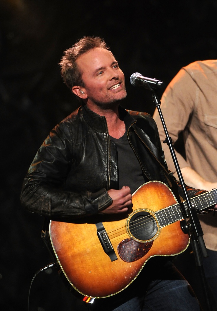 a man holding a guitar and singing into a microphone