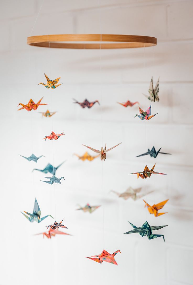 there are many origami birds hanging from the ceiling in front of a white wall