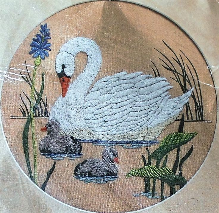 a white swan and two baby ducks in the water with blue flowers on it's side