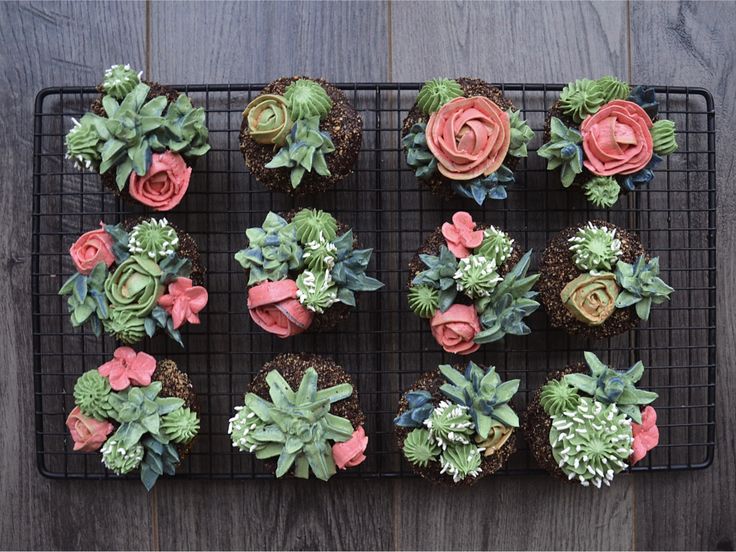 cupcakes decorated with flowers and succulents on a cooling rack