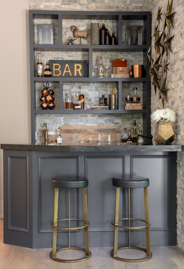 a bar with two stools in front of it and shelves on the wall behind it