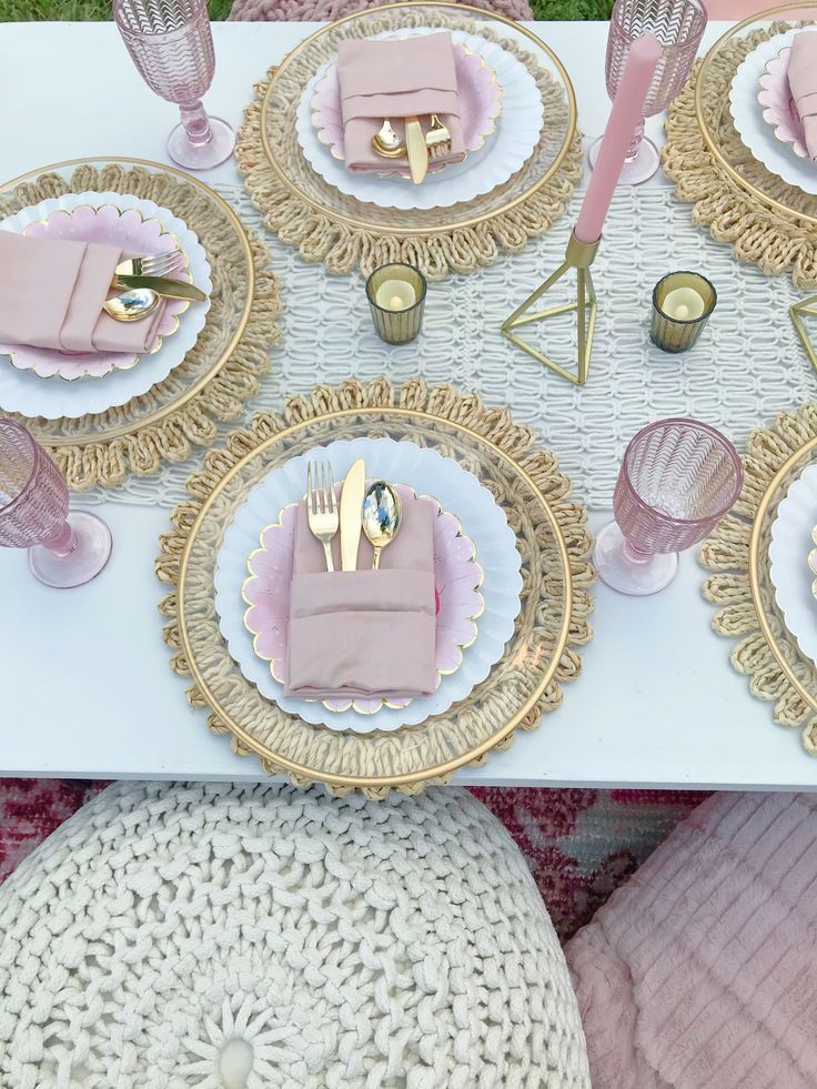 the table is set with pink and gold plates, napkins, and utensils